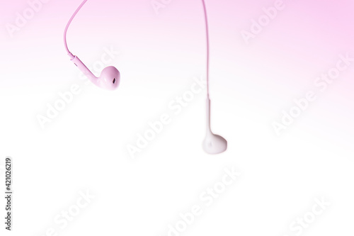 Earphones on pink and white background