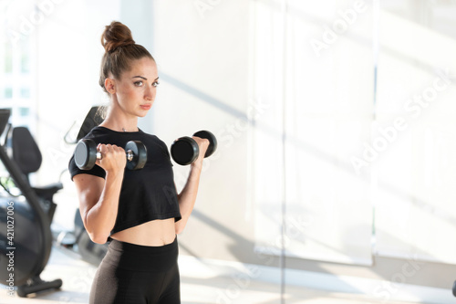 young sports woman lifting two dumbbells in gym © offsuperphoto
