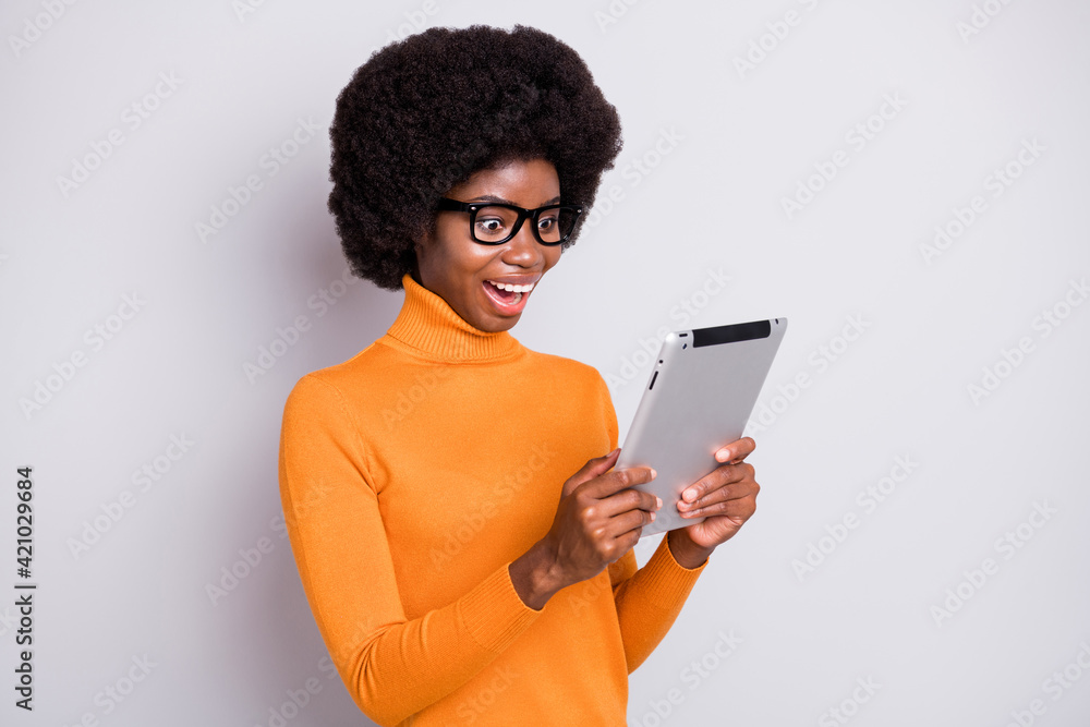 Photo portrait of amazed afro american woman holding tablet in two hands isolated on clear grey colored background Photo portrait of amazed afro american woman holding tablet in two hands isolated on clear grey colored background