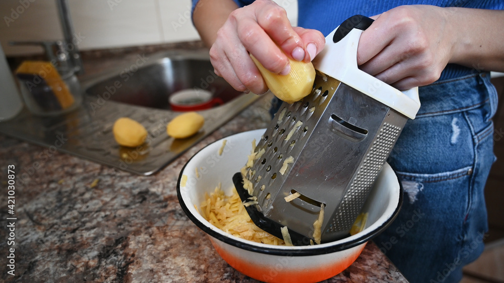 Close-up view of woman on the kitchen rubs potatoes on the grater Close-up view of woman on the kitchen rubs potatoes on the grater