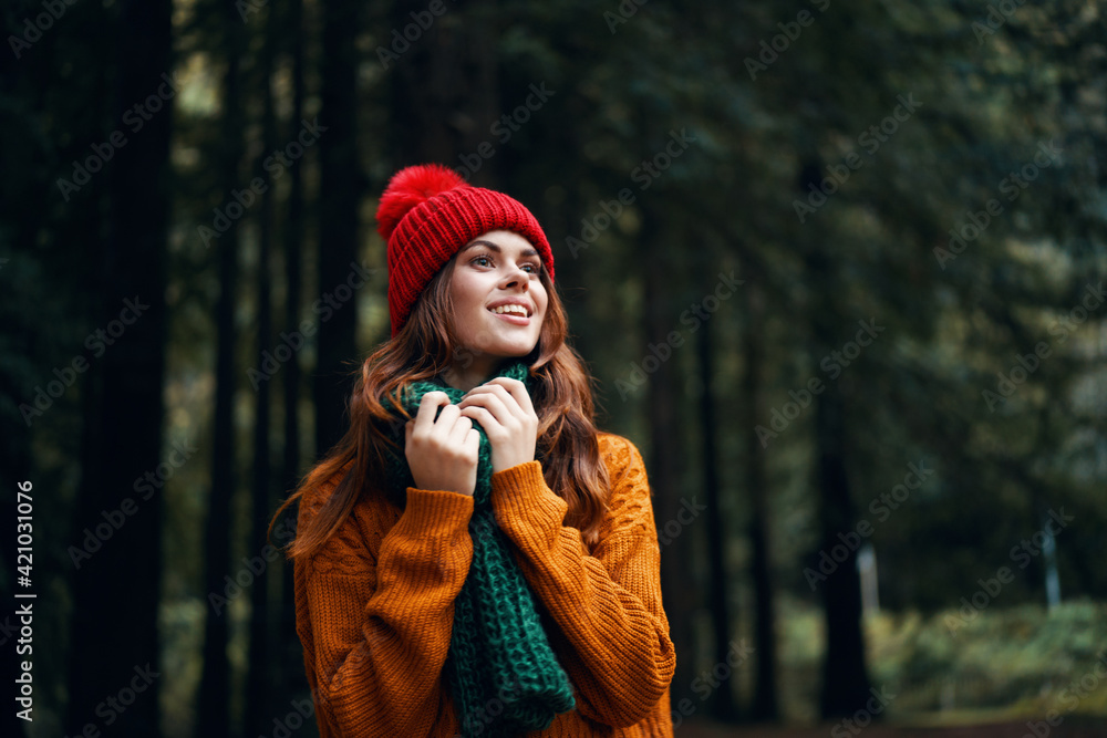 Happy woman in autumn sweater on the nature in the forest and a red hat Happy woman in autumn sweater on the nature in the forest and a red hat