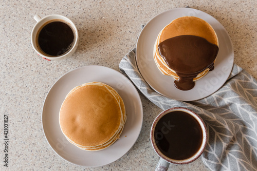 two plates with stacks of pancakes and coffee