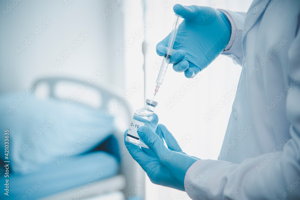 Doctor Young wearing gloves is preparing vaccine ready for treatment and control of COVID-19 on the side. Health care and medical Doctor Young wearing gloves is preparing vaccine ready for treatment and control of COVID-19 on the side. Health care and medical