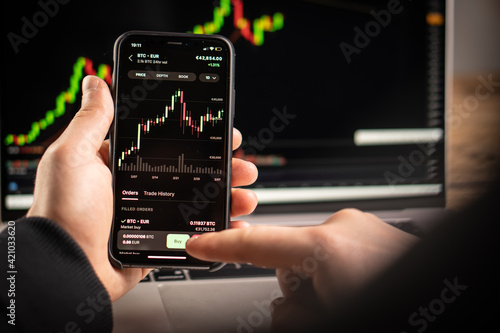 A man holds a phone in his hand and trades in cryptocurrencies on the stock exchange.