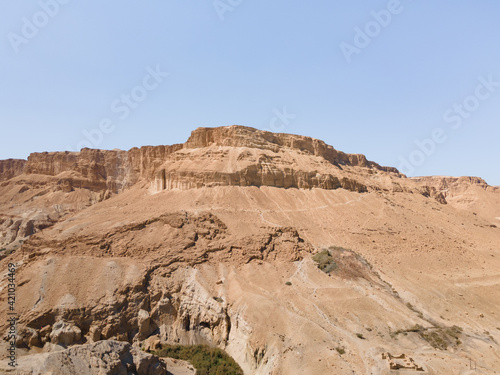 A sandy  mountain that used to be bottom of Dead Sea stands near Ein Bokek embankment on the coast of the Dead Sea  the sea itself and the mountains of Jordan visible in the distance  in Israel