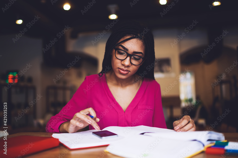 Serious black woman typing on smartphone while studying Serious black woman typing on smartphone while studying
