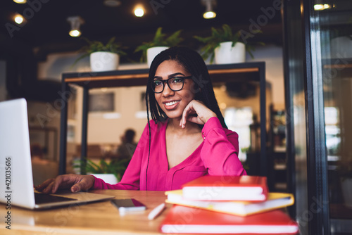 Cheerful black woman working with gadgets and notes in cafe