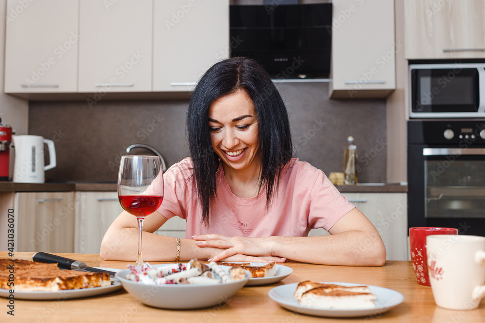 young dark-haired woman sits at the dining table in the kitchen young dark-haired woman sits at the dining table in the kitchen