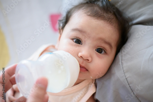 Cute little asian baby girl I was drinking from the bottle fed by my mother looking at the camera
