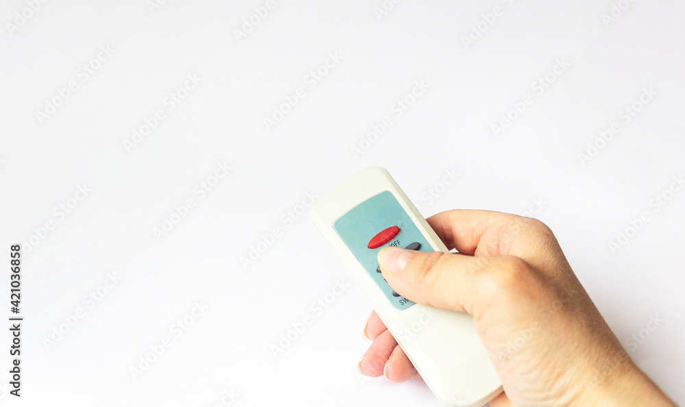 A female hand holds a remote control on a white background. A female hand holds a remote control on a white background.