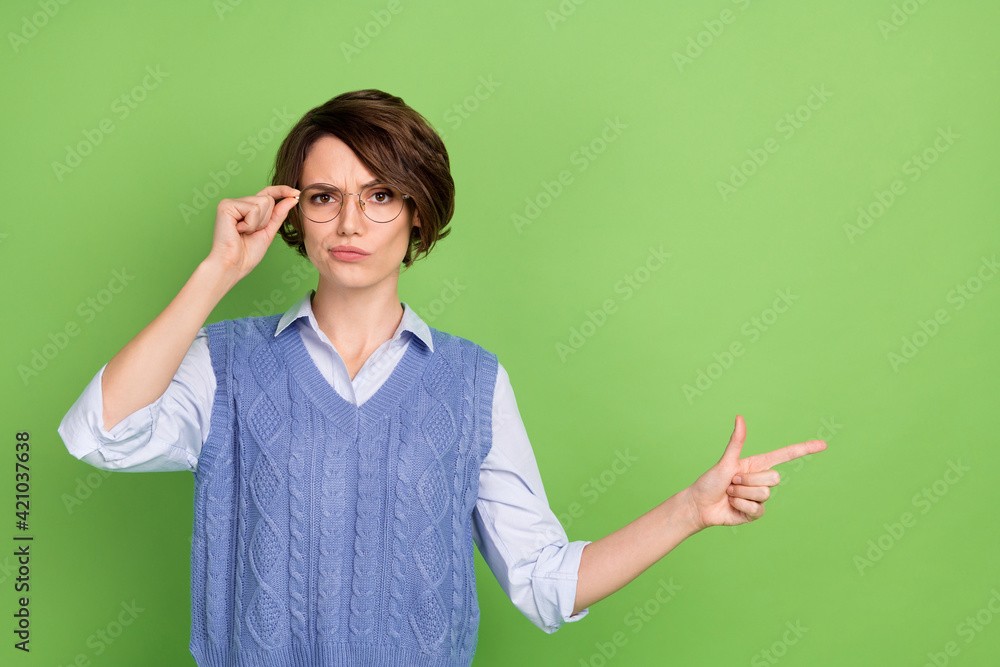 Photo portrait of young woman in spectacles pointing copyspace having doubt unsure isolated bright green color background Photo portrait of young woman in spectacles pointing copyspace having doubt unsure isolated bright green color background