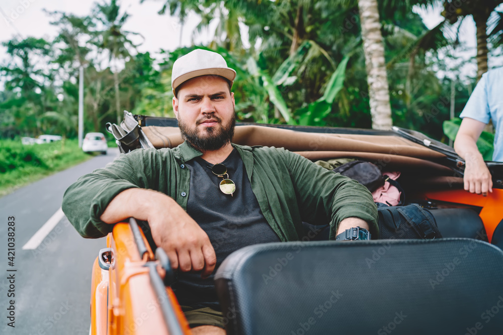Traveling hipster guy riding in car in tropics Traveling hipster guy riding in car in tropics