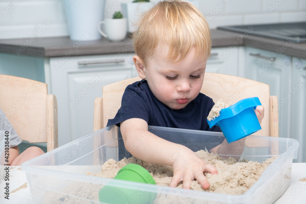 Baby boy playing with kinetic sand at home. Early age education. Toddler playing Baby boy playing with kinetic sand at home. Early age education. Toddler playing