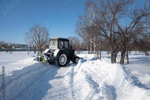 Tractor clears snow in the park in winter