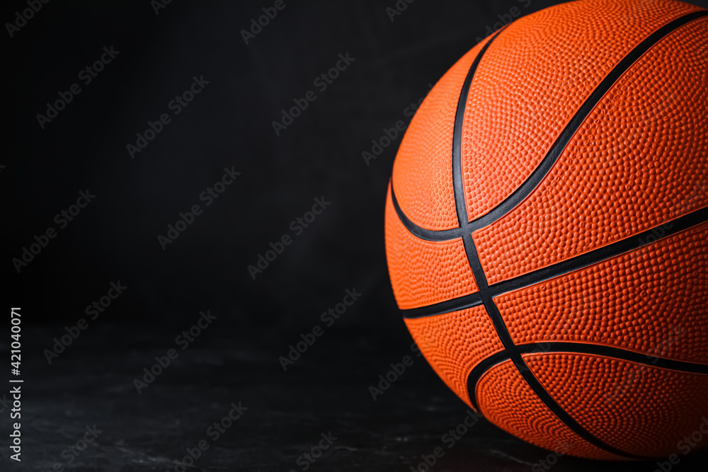 Fototapeta premium Orange ball on black background, space for text. Basketball equipment