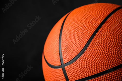 Closeup view of orange ball on black background  space for text. Basketball equipment