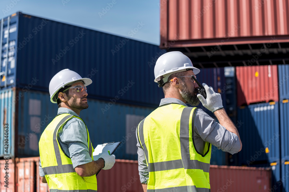 Logistics engineer and inspector working togetter and discussing in shipping containerin commercial transport port