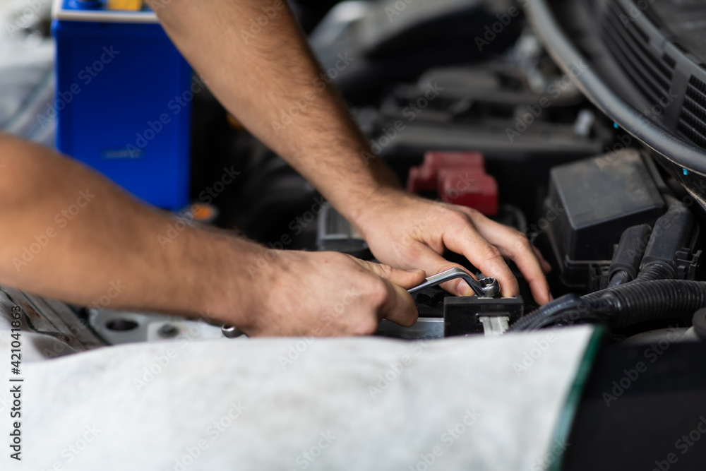 Obraz premium Auto mechanic worker checking and changing car battery. Car maintenance and auto service garage concept.