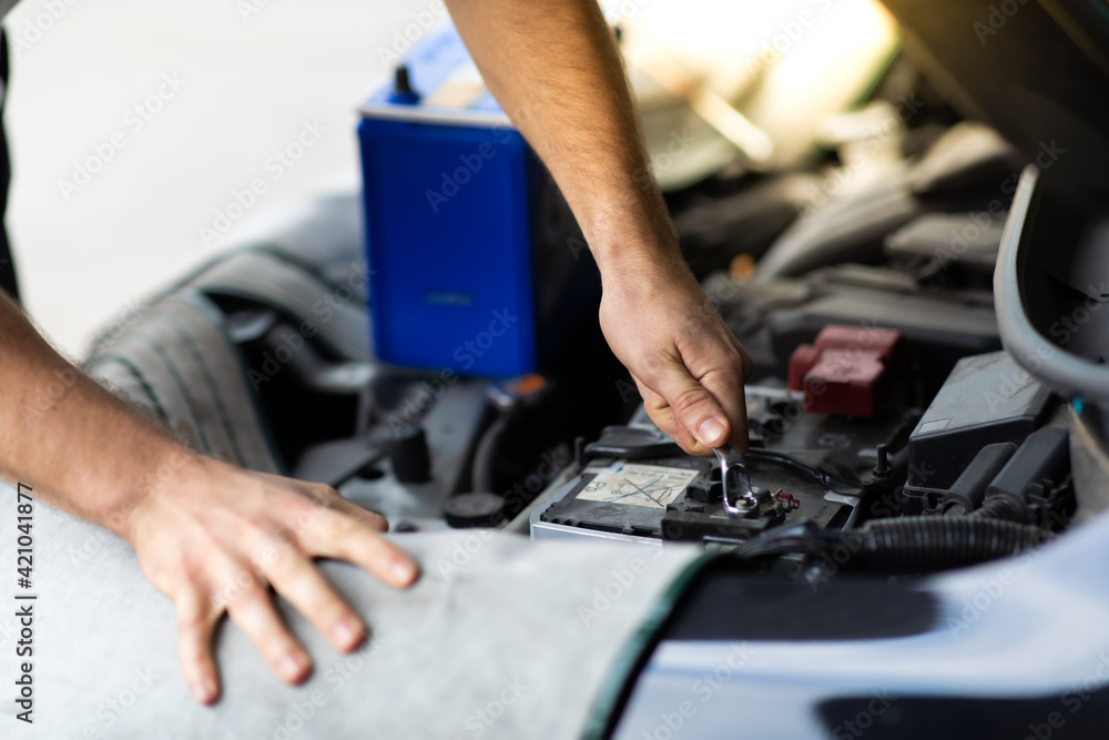 Auto mechanic worker checking and changing car battery. Car maintenance and auto service garage concept. Auto mechanic worker checking and changing car battery. Car maintenance and auto service garage concept.