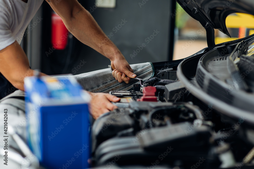 Auto mechanic worker checking and changing car battery. Car maintenance and auto service garage concept. Auto mechanic worker checking and changing car battery. Car maintenance and auto service garage concept.