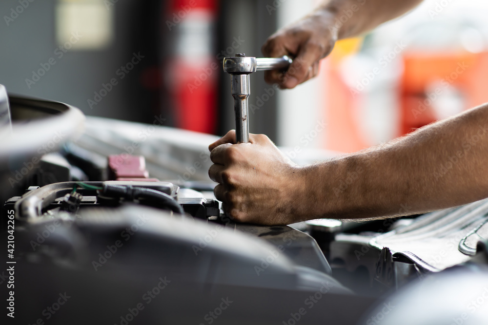 Caucasian male mechanic repairs car in garage. Car maintenance and auto service garage concept. Closeup hand and spanner. Caucasian male mechanic repairs car in garage. Car maintenance and auto service garage concept. Closeup hand and spanner.