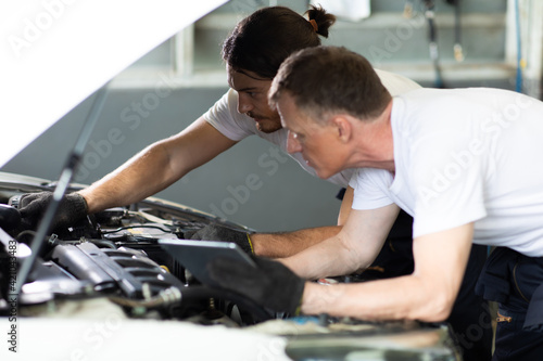 Two caucasian male mechanic repairs car in garage. Car maintenance and auto service garage concept. Closeup hand and spanner. teamwork concept.