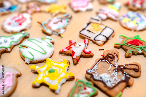 Hand decorated baked gingerbreads of various shapes, arranged on baking paper.