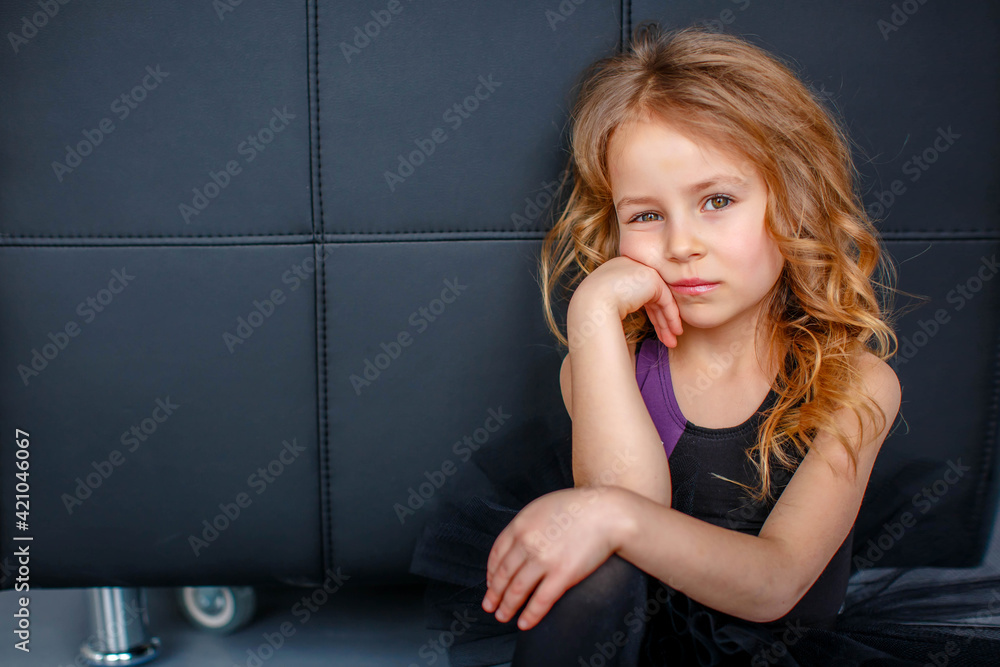 Little ballerina in a black tutu is bored sitting on the floor Little ballerina in a black tutu is bored sitting on the floor