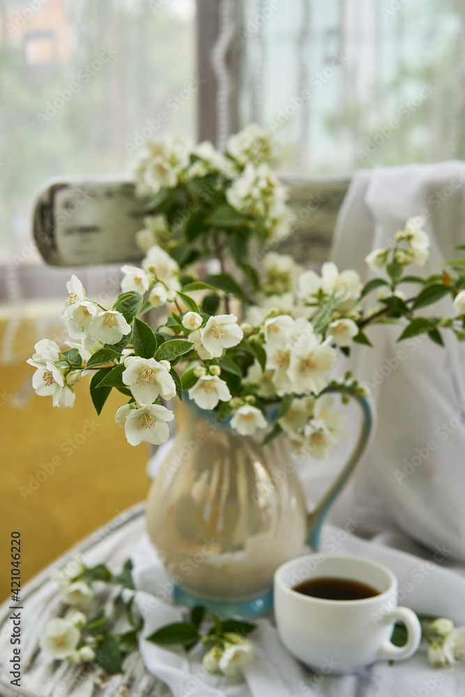 Jasmine flowers in a white vase. Stillife with jasmine and cup of coffee. Jasmine flowers in a white vase. Stillife with jasmine and cup of coffee.