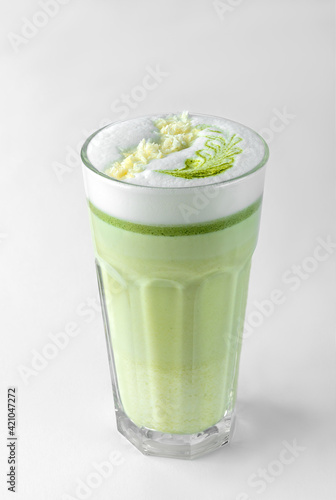 transparent glass with green coffee latte, frothed milk, syrup, whipped cream and topping