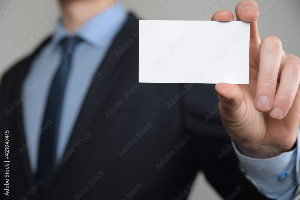 Businessman ,Business Man's hand hold showing business card - close up shot on grey background. Show a blank piece of paper. Paper visit card Businessman ,Business Man's hand hold showing business card - close up shot on grey background. Show a blank piece of paper. Paper visit card
