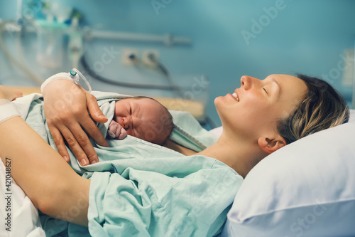 Mother and newborn. Child birth in maternity hospital. Young mom hugging her newborn baby after delivery. Woman giving birth. photo