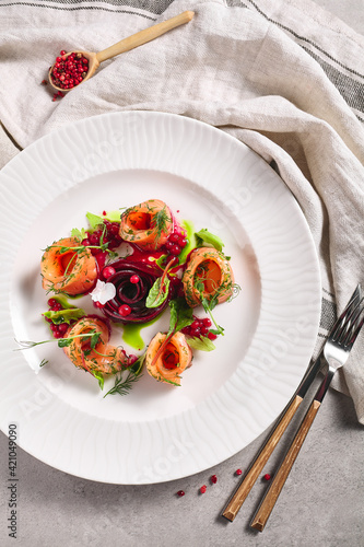 Cured Salmon Gravlax with Beet and Berries. Salted fish fillet with beetroot and dill in white plate on table. Gourmet, swedish, scandinavian seafood concept. photo