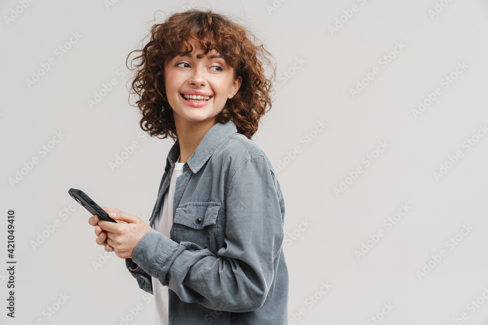 Fototapeta premium Young ginger joyful woman smiling while using mobile phone