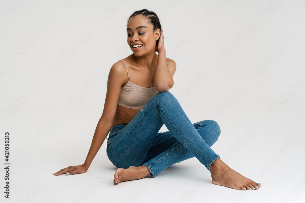 Young african woman wearing brassiere smiling while sitting on floor