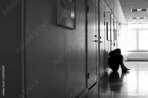 Sad unrecognizable young person sitting in hospital corridor.