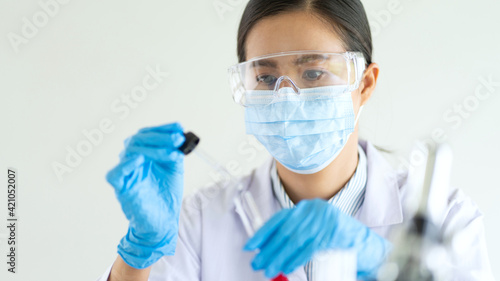 Young Asian scientist Working looking through a microscope doing research for analyzing a Experiments sample in a forensic laboratory.