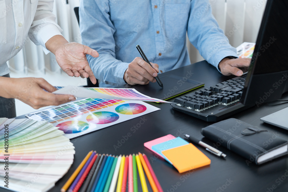 graphic designer team working on web design using color swatches editing artwork using tablet and a stylus at desks In creative office graphic designer team working on web design using color swatches editing artwork using tablet and a stylus at desks In creative office
