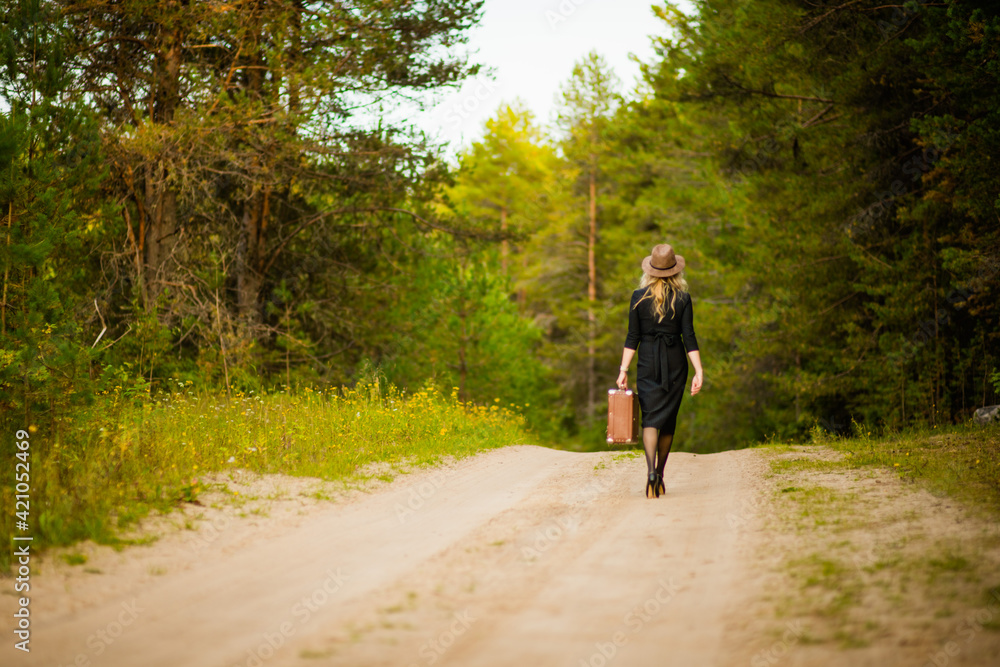 blonde girl in black dress with suitcase, selective focus