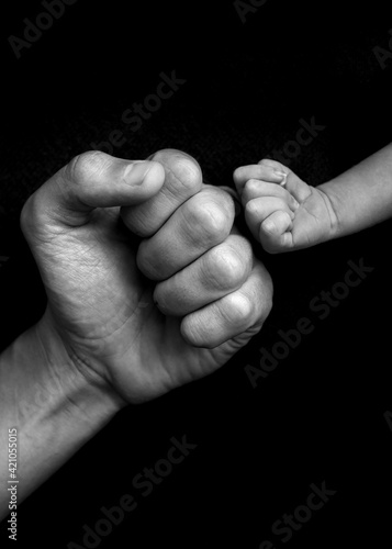 hands fists father and son on black background, black and white 