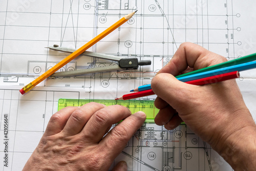 The planner makes a drawing of the building with coloured pencils. The porous texture of the drawing paper. Graphite pencil, compass, ruler lie on the drawing