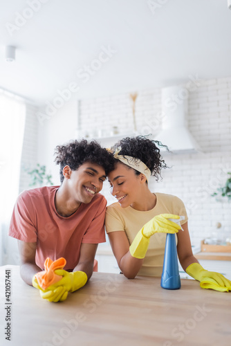 Young african american couple smiling while cleaning kitchen