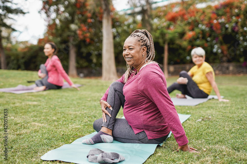 Multiracial women doing yoga exercise with social distance for coronavirus outbreak at park outdoor - Healthy lifestyle and sport concept