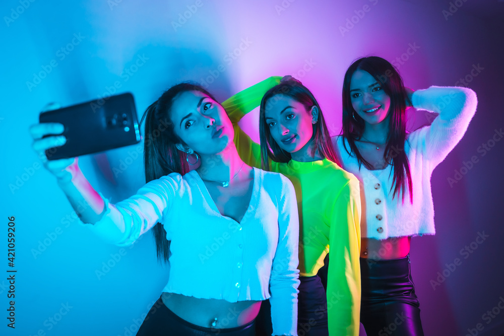 Lifestyle of friends partying in a nightclub with blue and pink neon lights, taking a selfie with the phone Lifestyle of friends partying in a nightclub with blue and pink neon lights, taking a selfie with the phone