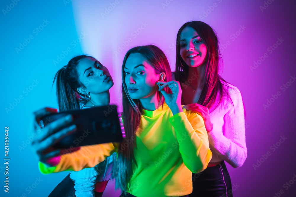 Lifestyle of friends partying in a disco with blue and pink neon lights, having fun taking a photo for social networks Lifestyle of friends partying in a disco with blue and pink neon lights, having fun taking a photo for social networks