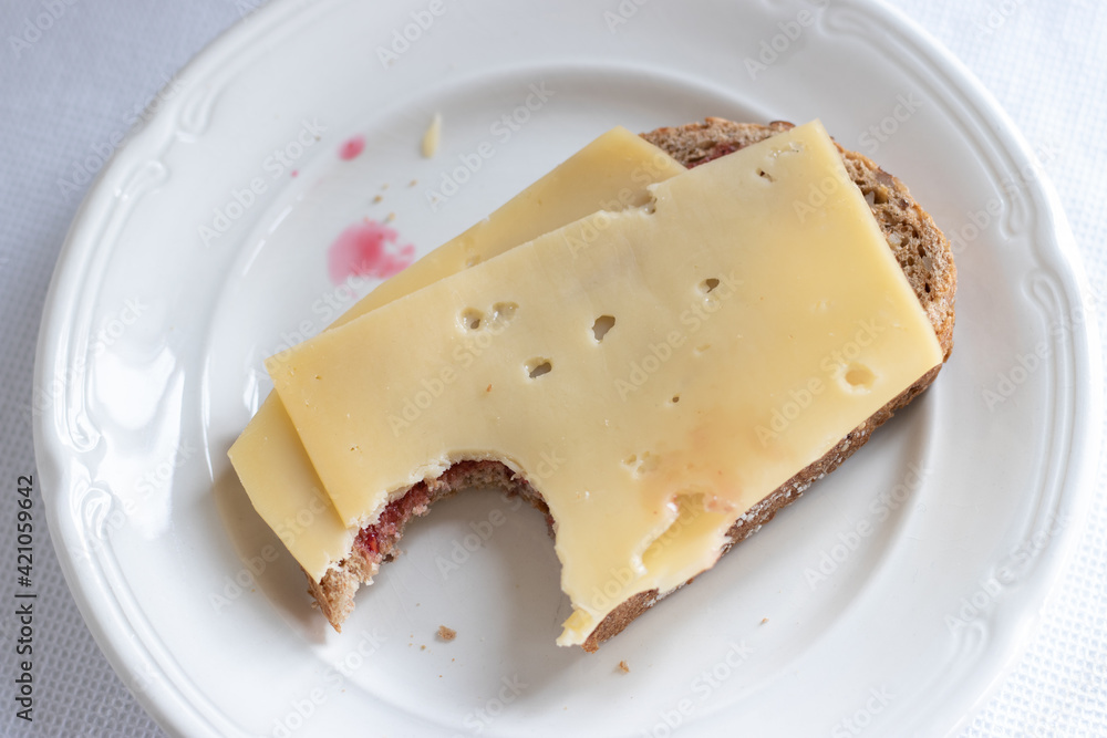 A bite of a Slice of bread with cheese on white plate