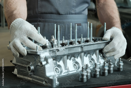 Car spare parts.The cylinder head of an internal combustion engine.Close-up of the mechanic's hands.Product control.Installation of condensers.Preparation for installation.Repair and maintenance.