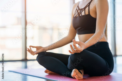 Cropped photo of girl who is meditating while sitting in the lotus position. Woman doing yoga