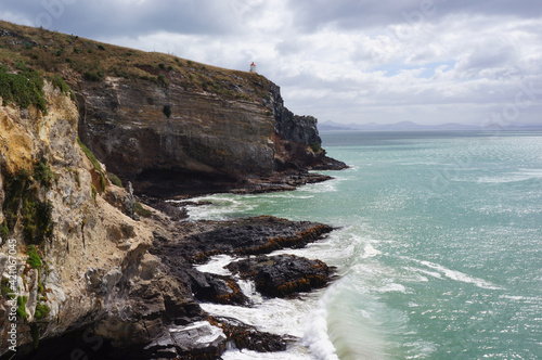 Scenic Cliff landscape with dramatic clouds and small lighthouse in the back