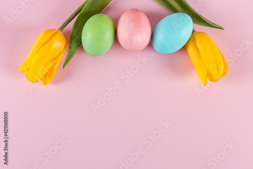 Easter colored eggs and tulips on a pink background. Copy space.